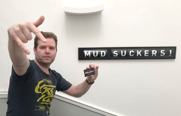Steven doing a gansta stance beside a sign which reads "mud suckers!"